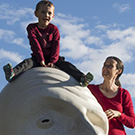 child sitting on sculpture next to mom 