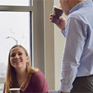 girl sitting and man standing with coffee