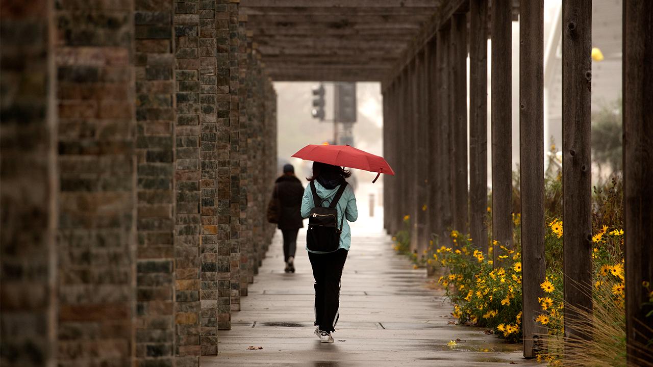 girls walks in the rain with red umbrella