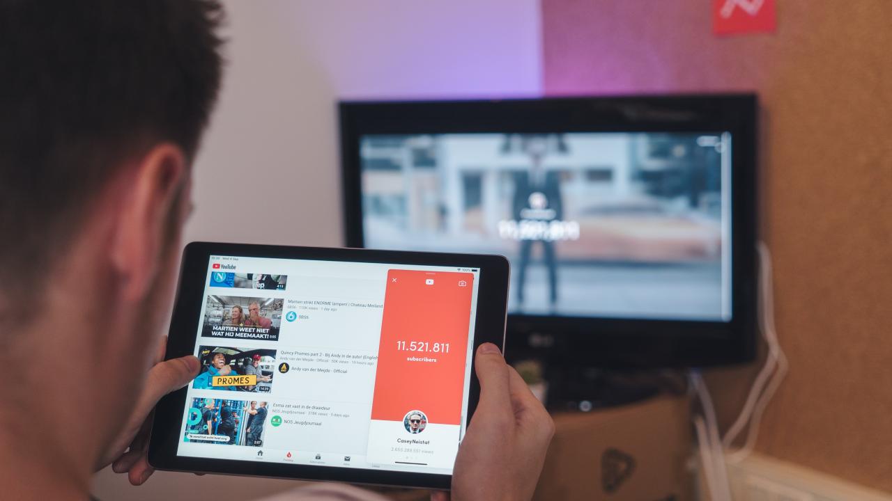 man watches video on tablet with computer in background