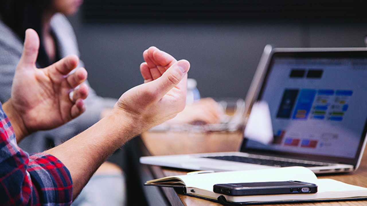 mans hands next to notebook and open computer