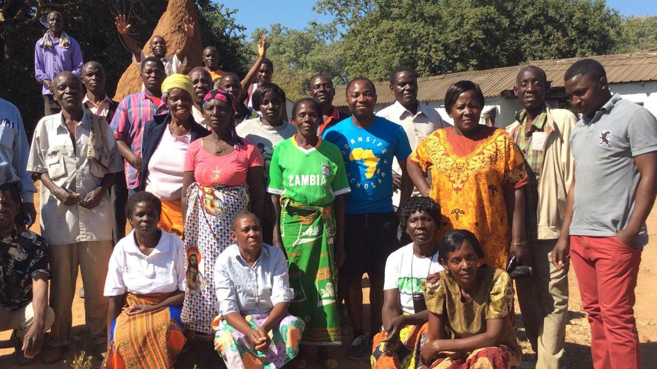 group of adults standing in a village in zambia 