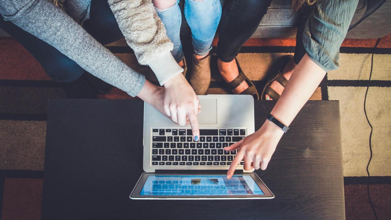 fingers pointing at a computer screen 