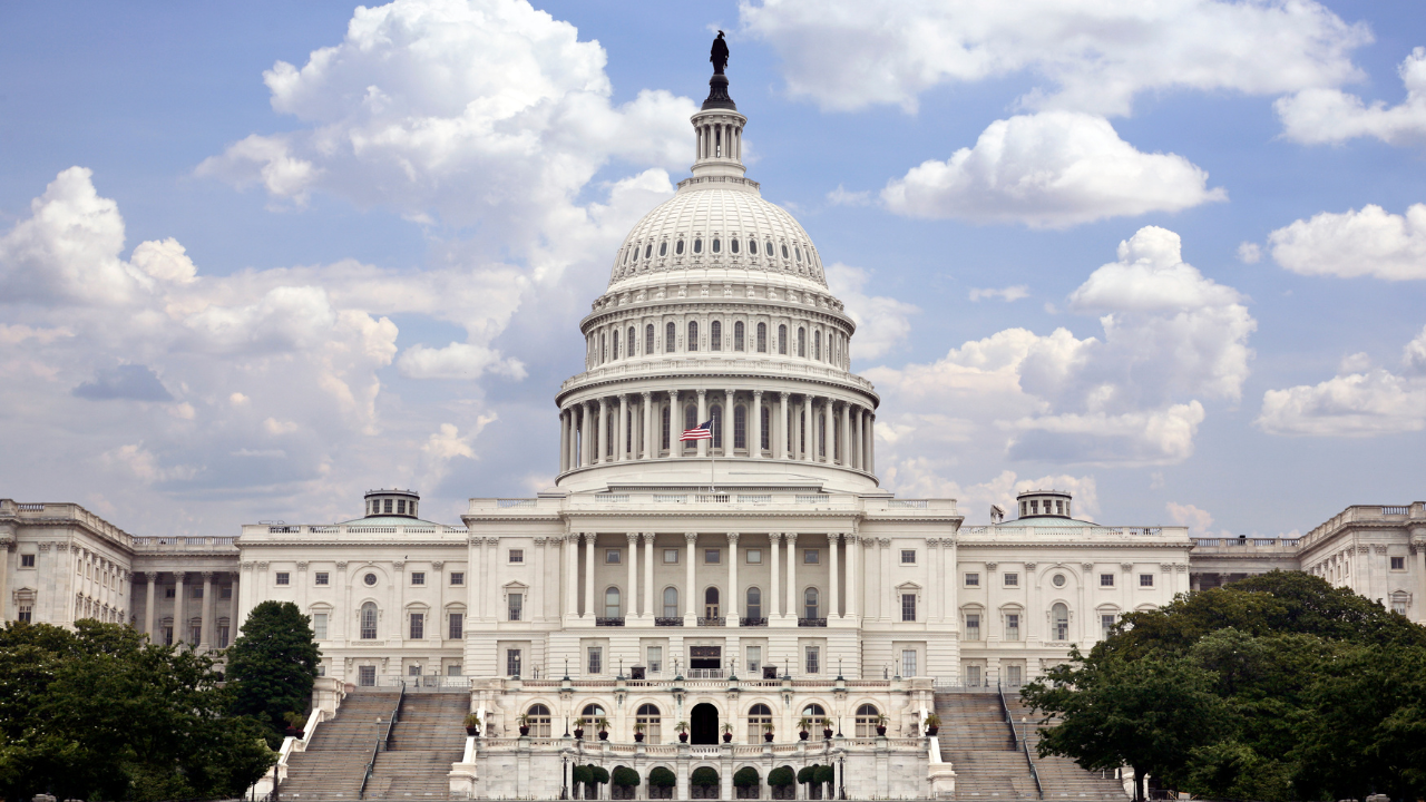 The United States Capitol Building against a blue sky peppered with clouds.