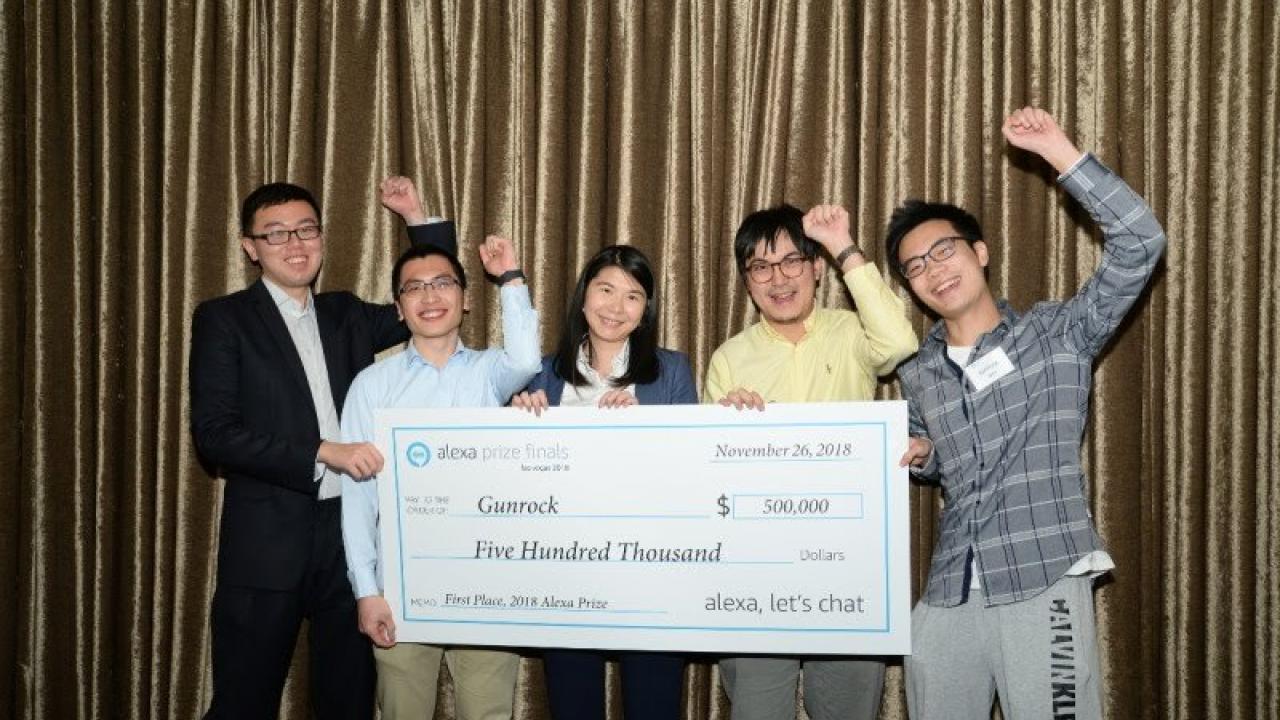 Five students celebrate with giant check