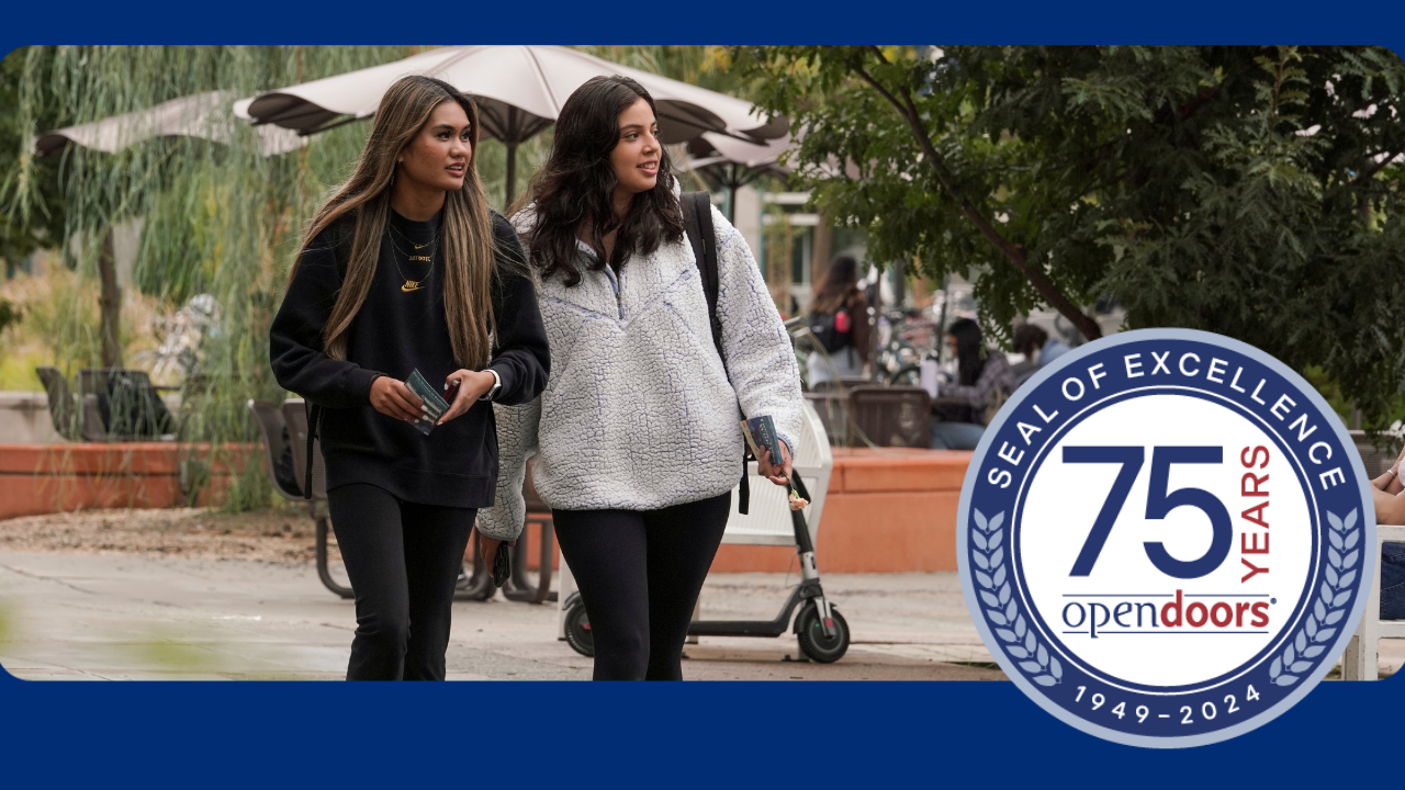 Two students walk through campus, looking off into the distance.
