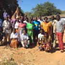 group of adults standing in a village in zambia 