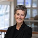 Karen smiles in a black shirt and blazer in the International Center.