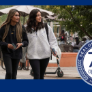 Two students walk through campus, looking off into the distance.