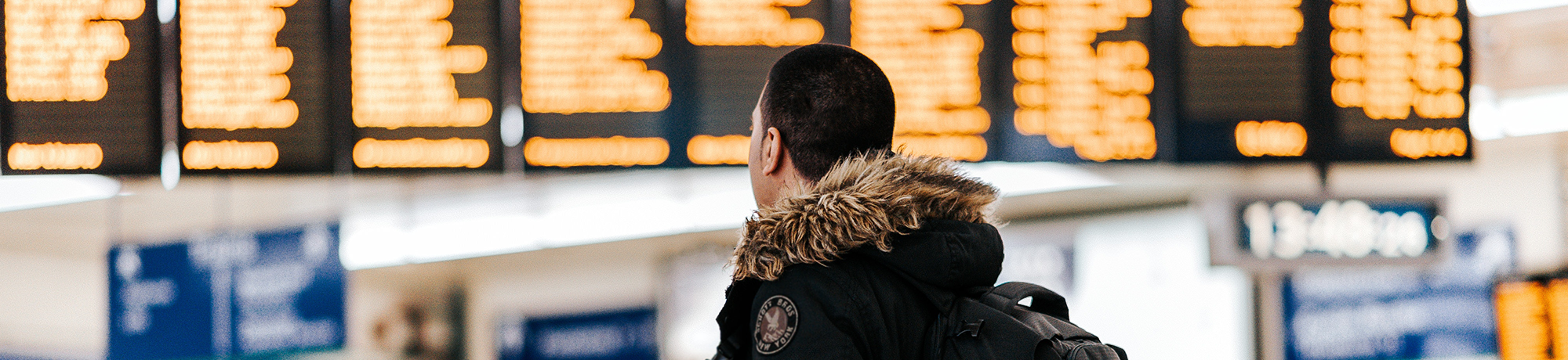 man looking at airport arrival and departure screens